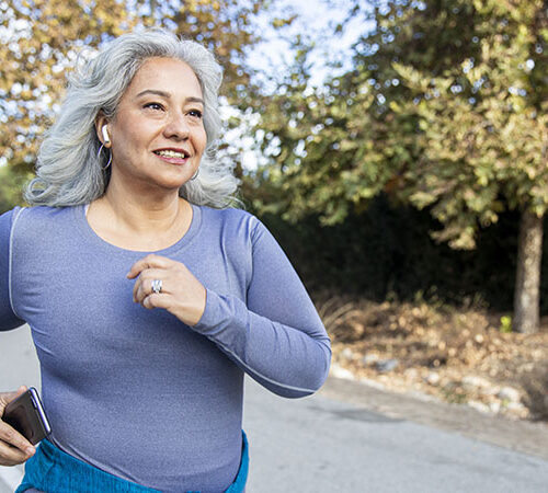 A mature Mexican woman jogging on a trail